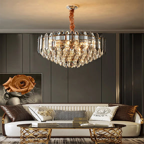 A luxurious living room features the Lazzo Modern Chandelier by Morsale, adorned with LED bulbs that illuminate a white sofa accented with patterned pillows and a round glass coffee table. The contemporary style is highlighted by dark paneled walls and elegant decor, complemented by large floral artwork on the wall.