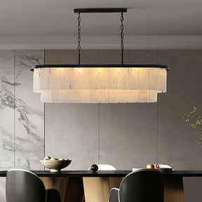 A modern dining room highlights the Morsale Natural Marble Dining Room Chandelier, featuring sleek LED lighting with layered shades, gracefully suspended over a marble-topped table. This dimmable fixture lights up a set of four upholstered chairs and a decorative bowl of fruit, all beautifully framed by an eye-catching marble accent wall.