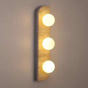 The Natural Travertine Stone LED Wall Lamp by Morsale.com features a modern vertical rectangular base and three evenly spaced, illuminated spherical bulbs that cast a warm, ambient LED light against a neutral background. The base, reminiscent of Art Deco design, is crafted from stone-like travertine with a smooth, curved edge on the left side.