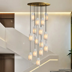 A set of Moonshade Natural Marble Pendant Lights from Morsale, epitomizing luxury lighting, hangs from the ceiling. It's positioned near a staircase featuring sleek, minimalist design elements with wooden wall accents and white walls, creating an elegant ambiance.