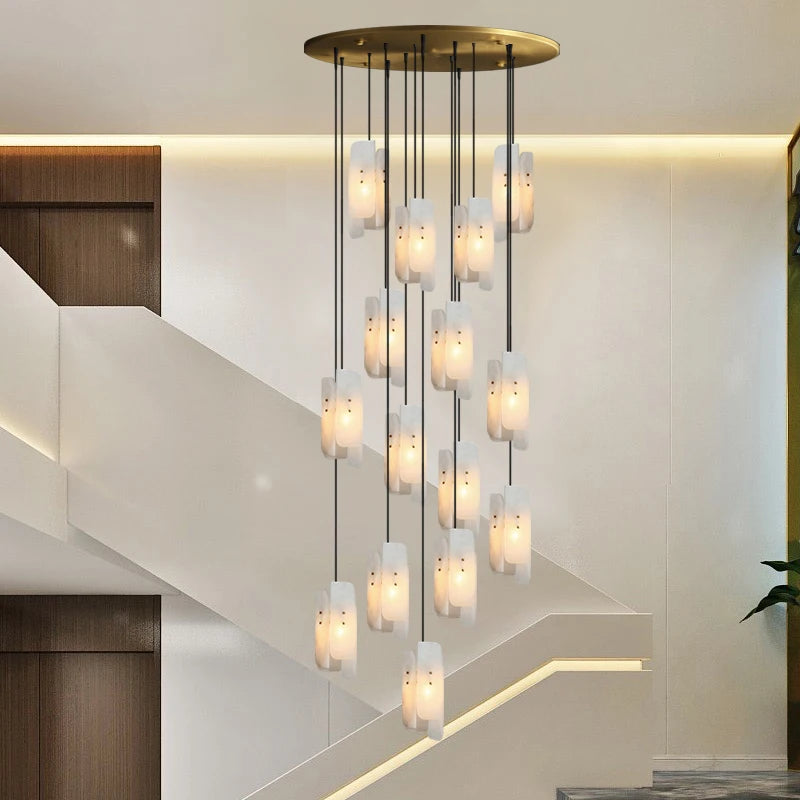 A set of Moonshade Natural Marble Pendant Lights from Morsale, epitomizing luxury lighting, hangs from the ceiling. It's positioned near a staircase featuring sleek, minimalist design elements with wooden wall accents and white walls, creating an elegant ambiance.