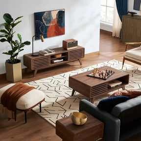 A stylish living room features the Morsale Ensley Wood Coffee Table, which doubles as a chessboard, a mid-century TV stand, abstract wall art, a potted plant beside the comfy sofa, and is beautifully illuminated by large windows with blue curtains.