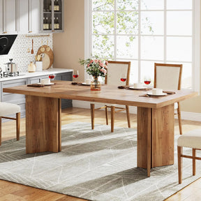 The Tribesigns 63-inch dining table by Morsale sits in a bright room with large windows, showcasing a minimalist modern style. It features a floral centerpiece, four place settings with red wine glasses, cushioned chairs, and rests on a patterned rug with visible kitchen elements.