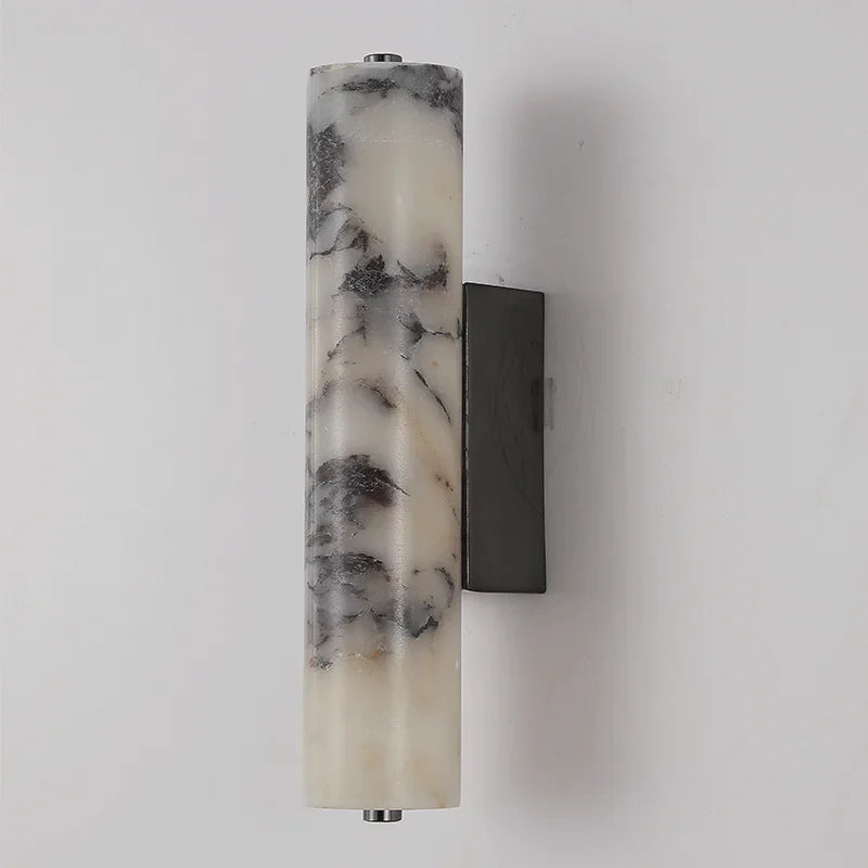 
                  
                    The Morsale Valmont Marble Cylinder Sconce features a cylindrical black and white marbled glass shade mounted on a rectangular black metal backplate against a plain white wall.
                  
                