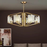 The Morsale Jeff Morgan Ceiling Lights, a modern gold chandelier with geometric lines and frosted glass panels fitted with LED bulbs, illuminate the space above a neutral sofa, while an abstract portrait decorates the wall behind.