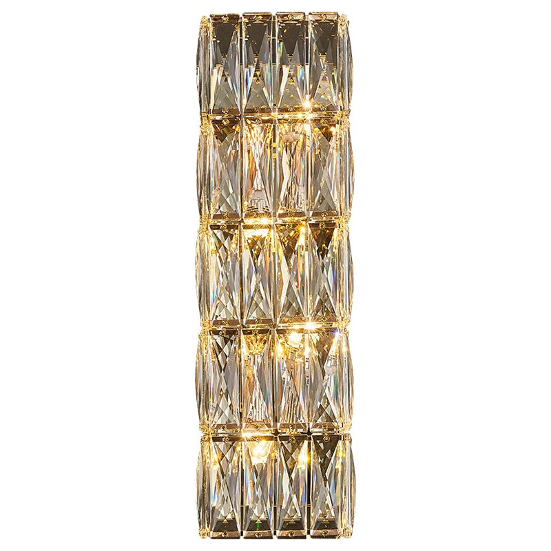 Introducing the Bacci Crystal Wall Sconce by Morsale, a vertically oriented and elegant lighting fixture featuring multiple rectangular, faceted crystal panels that reflect warm light from LED bulbs. The crystals are arranged in a grid pattern, creating a sparkling and luxurious appearance that seamlessly blends with modern style.