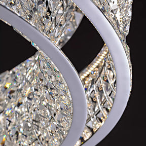 The Bacci Modern Crystal Chandelier by Morsale showcases intricate spiraling metallic arms and dazzling crystal embellishments. Illuminated by LED bulbs, it reflects light beautifully, creating a sparkling effect against a dark background.