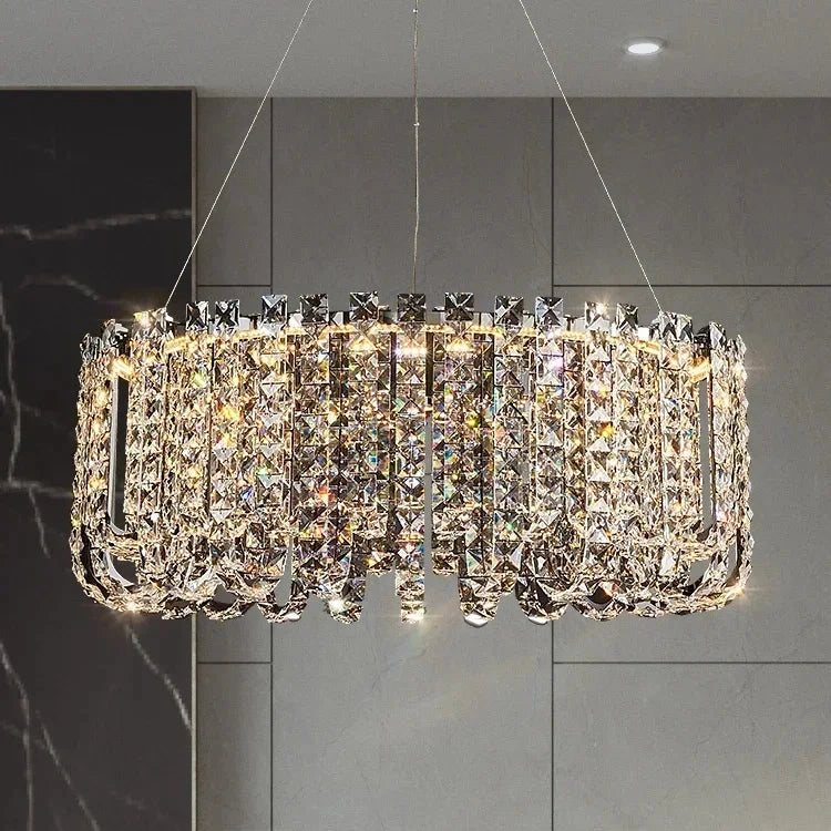 A large, circular Morsale Bacci Crystal Beads Chandelier with exquisite craftsmanship and numerous crystal pendants hangs from the ceiling. It casts a luxurious glow against a neutral-toned, modern backdrop with gray paneled walls, creating a stunning sparkling effect.