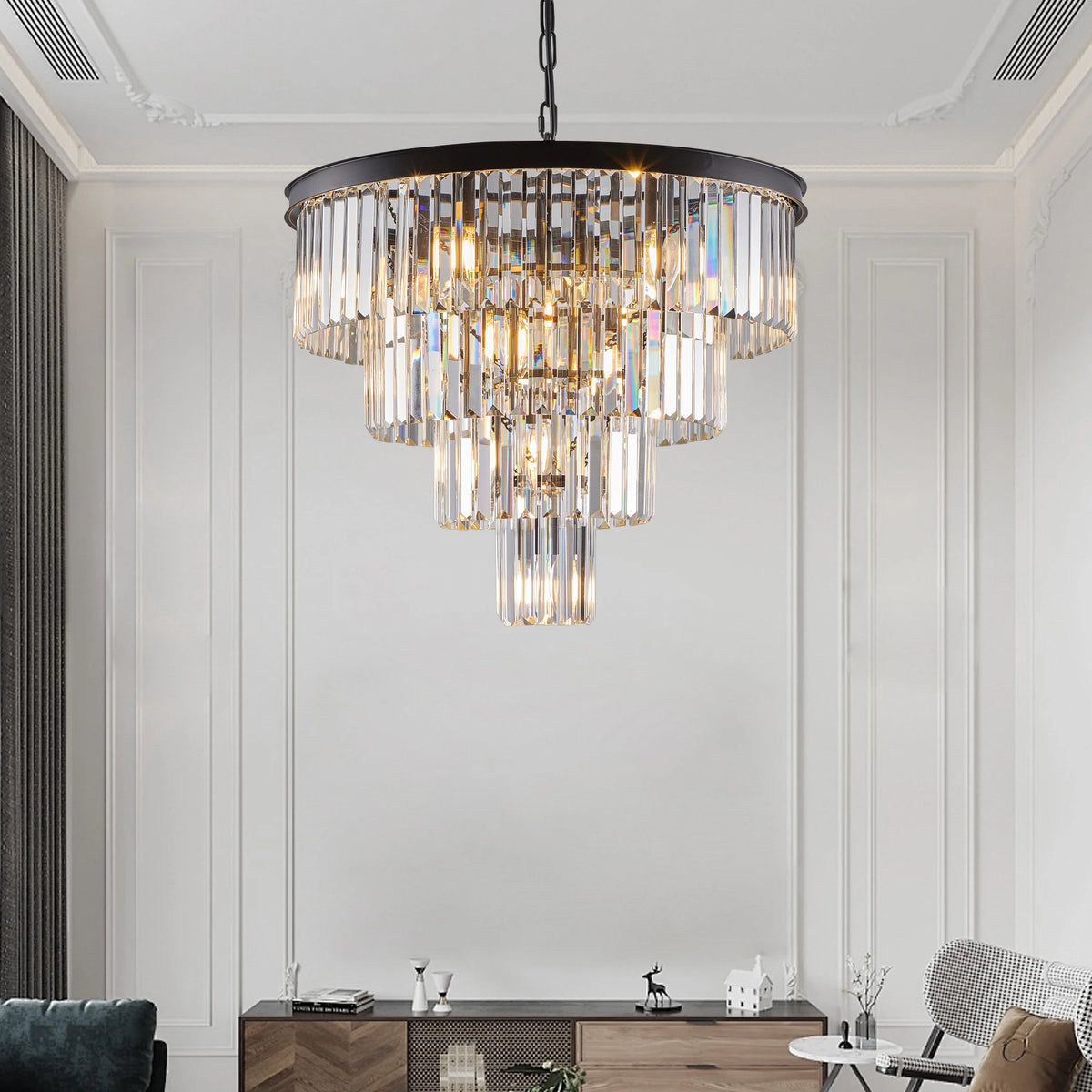 A modern room with tall white walls showcases the 23.6" Gio Crystal Chandelier by Morsale, featuring multiple tiers of glass pendants. Below, a wooden sideboard holds decor, while a grey curtain and chair complete the elegant design, embodying contemporary sophistication.