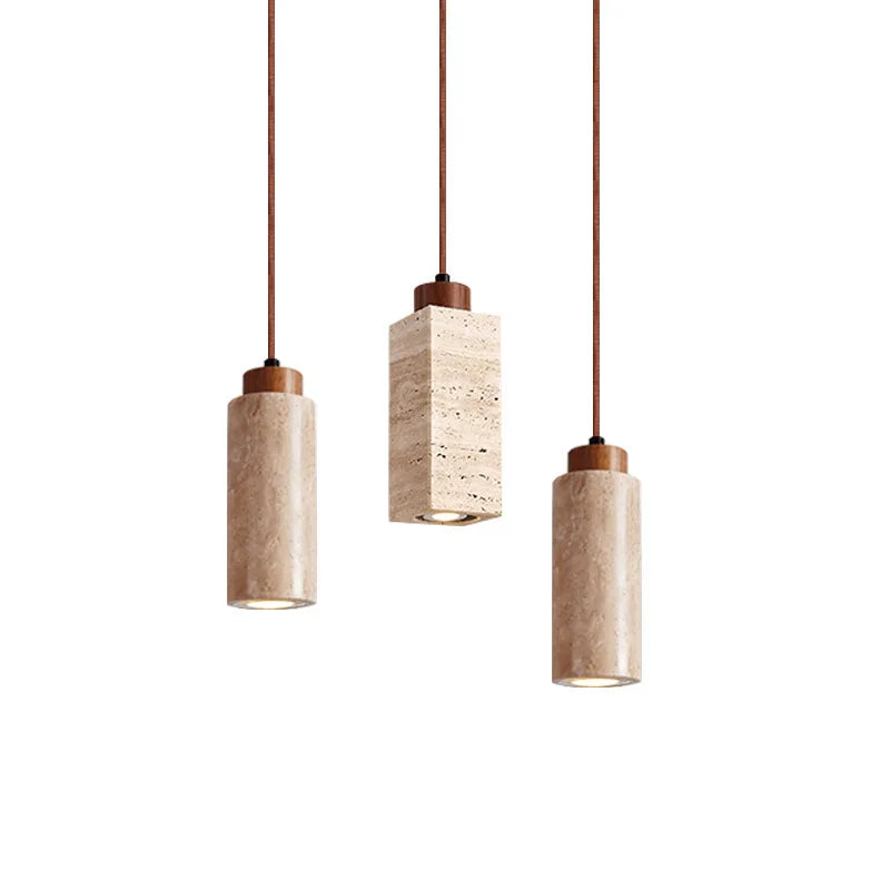 Three Natural Travertine Pendant Lights from Morsale.com with cylindrical beige shades hang from the ceiling. The central light, elegantly crafted from travertine, showcases a square, stone-like shade, while the two on either side feature round, smooth shades. All lights include LED bulbs and matching brown cords for a cohesive look.