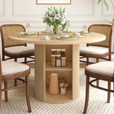 The Morsale Harrow 47" Round Dining Table with Storage showcases light gray plates, wine glasses, and gray napkins, complemented by four wicker chairs. A vase of white roses centers the table, while the base provides shelving for organizing a jug and dishes.