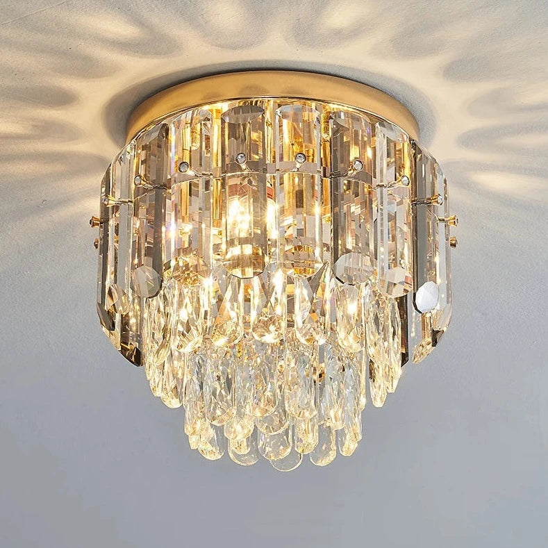 The Morsale.com Giano Ceiling Light Fixture is a round gold-framed masterpiece adorned with multiple handmade crystal glass prisms. When illuminated, this flush mount casts a pattern of reflections and shadows onto the ceiling, resulting in an elegant and sparkling overall appearance.