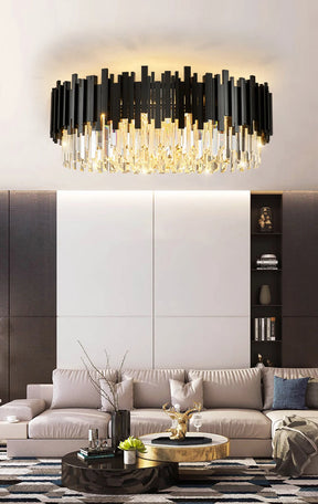 An elegant living room features the Morsale Gio Modern Chandelier with crystal shades above a light gray sofa with pillows, set against a contemporary beige and dark brown wall. A round coffee table with decorative items sits on a patterned rug.