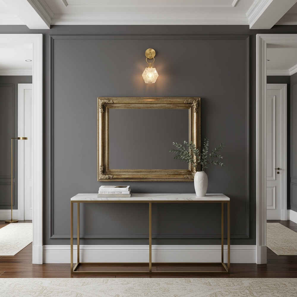 
                  
                    A modern hallway features a gold-framed empty picture frame on a dark gray wall, a white vase with greenery on a marble console table with gold legs, and the Morsale Emilia Copper & Glass Wall Pendant illuminating above the frame.
                  
                