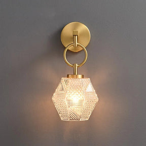 A sleek Copper & Glass Pendant Wall Sconce by Morsale is mounted on a gray wall, showcasing its geometric design. It includes a copper circular mount and loop that supports a hexagonal textured glass light cover, casting a warm LED glow.