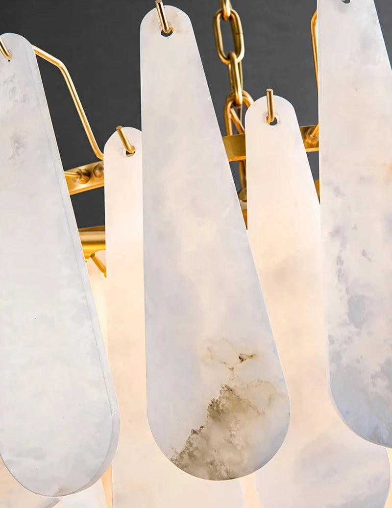 Close-up of the Moonshade Marble Chandelier by Morsale, showcasing a modern design with large, teardrop-shaped marble panels hanging from gold chains. The semi-translucent panels reveal natural textures and patterns, while energy-efficient LED bulbs enhance its elegant aesthetic.