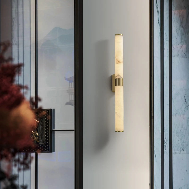 The 27" Moonshade Natural Marble & Copper Wall Sconce by Morsale is elegantly mounted on a sleek, white wall. The room showcases contemporary style decor with elements of nature visible through the transparent panels.