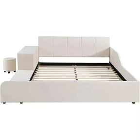 The Morsale Chenille Queen Size Bed features a modern white frame with a tall cushioned headboard and side panels in elegant velvet. The visible slatted base pairs with a matching cylindrical ottoman and rectangular bedside desk, offering a minimalistic, contemporary design.