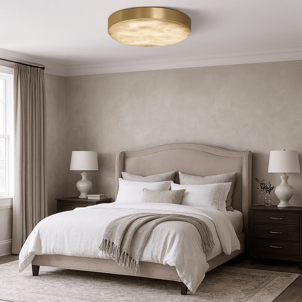 A cozy bedroom with a beige upholstered bed, white bedding, two dark wood nightstands with matching lamps, a textured rug, curtains, and the Morsale Laurel Marble Flush Mount ceiling light. The walls are light beige.