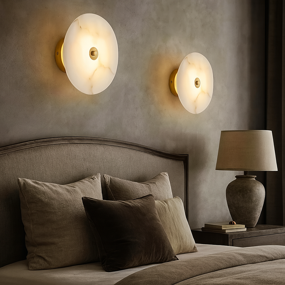 
                  
                    A modern bedroom featuring a beige upholstered headboard, neutral bedding, a stone-like lamp on the bedside table, and two Morsale.com Hastings Marble Wall Sconces with integrated LED lighting on a textured gray wall.
                  
                
