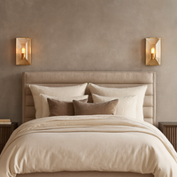 A neatly made bed with beige and brown bedding sits against a taupe wall, flanked by Brookhill Crystal Wall Sconces from Morsale.com. The sconces add modern luxury lighting above the dark nightstands on each side.