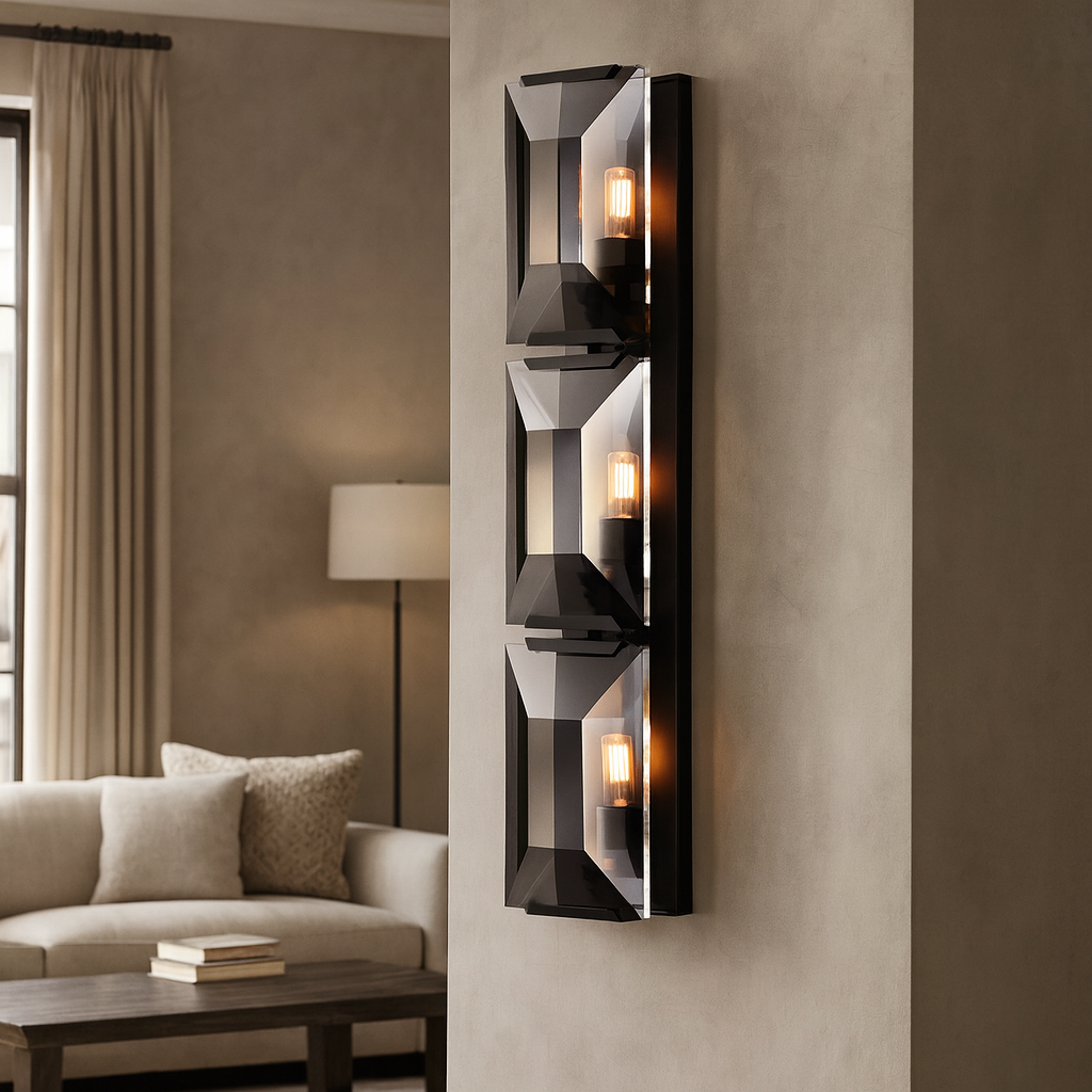 The Brookhill Crystal Wall Sconce by Morsale.com features three vertical glass fixtures, casting warm light in a neutral living room accented by a sofa, cushions, lamp, and tall curtains.