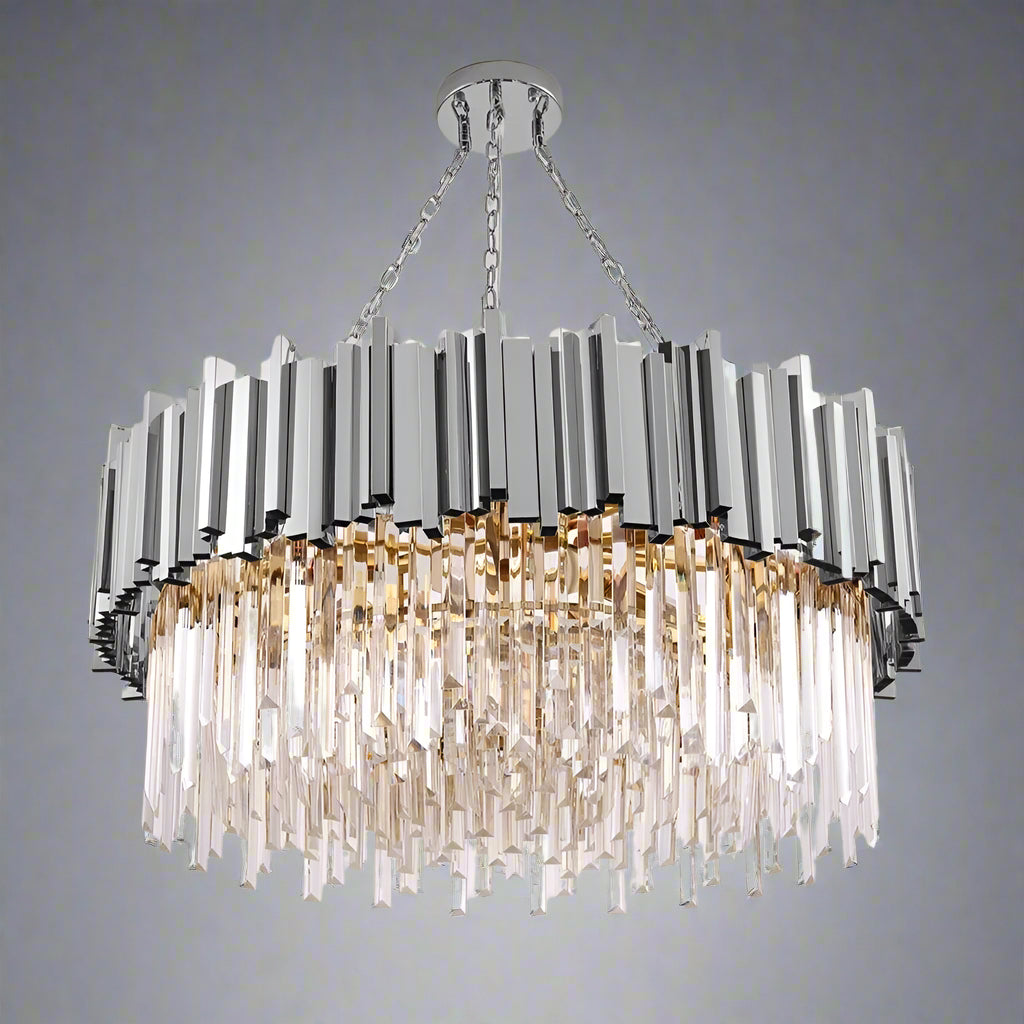 The Gio Stainless Steel & Crystal Modern Chandelier by Morsale.com hangs from a silver chain, showcasing a circular design. Crafted from premium materials, it features silver rectangular metal panels on the top and multiple crystal-like hanging pieces that create a cascade effect. The elegant lighting fixture is turned on, casting a warm glow.