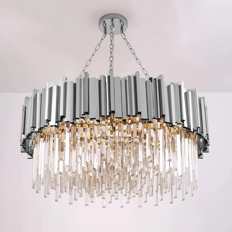 A luxurious, modern chandelier with a circular design, the Gio Crystal Chandelier, Polished Chrome by Morsale.com features an arrangement of metallic rectangular elements in polished stainless steel cascading downwards. Thin, elongated handmade clear crystals hang at varying lengths, reflecting light and adding sparkle to the fixture.