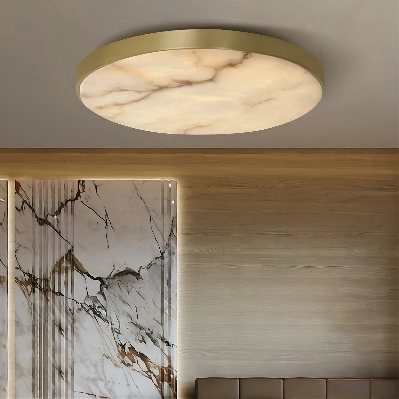 The Moonshade Marble & Copper Ceiling Light by Morsale, featuring a modern round design with a marble-like pattern and copper rim, is installed on a beige ceiling. This elegant light piece enhances the room's decor, which includes a wall featuring a complementary marble motif and furnishings in neutral tones.