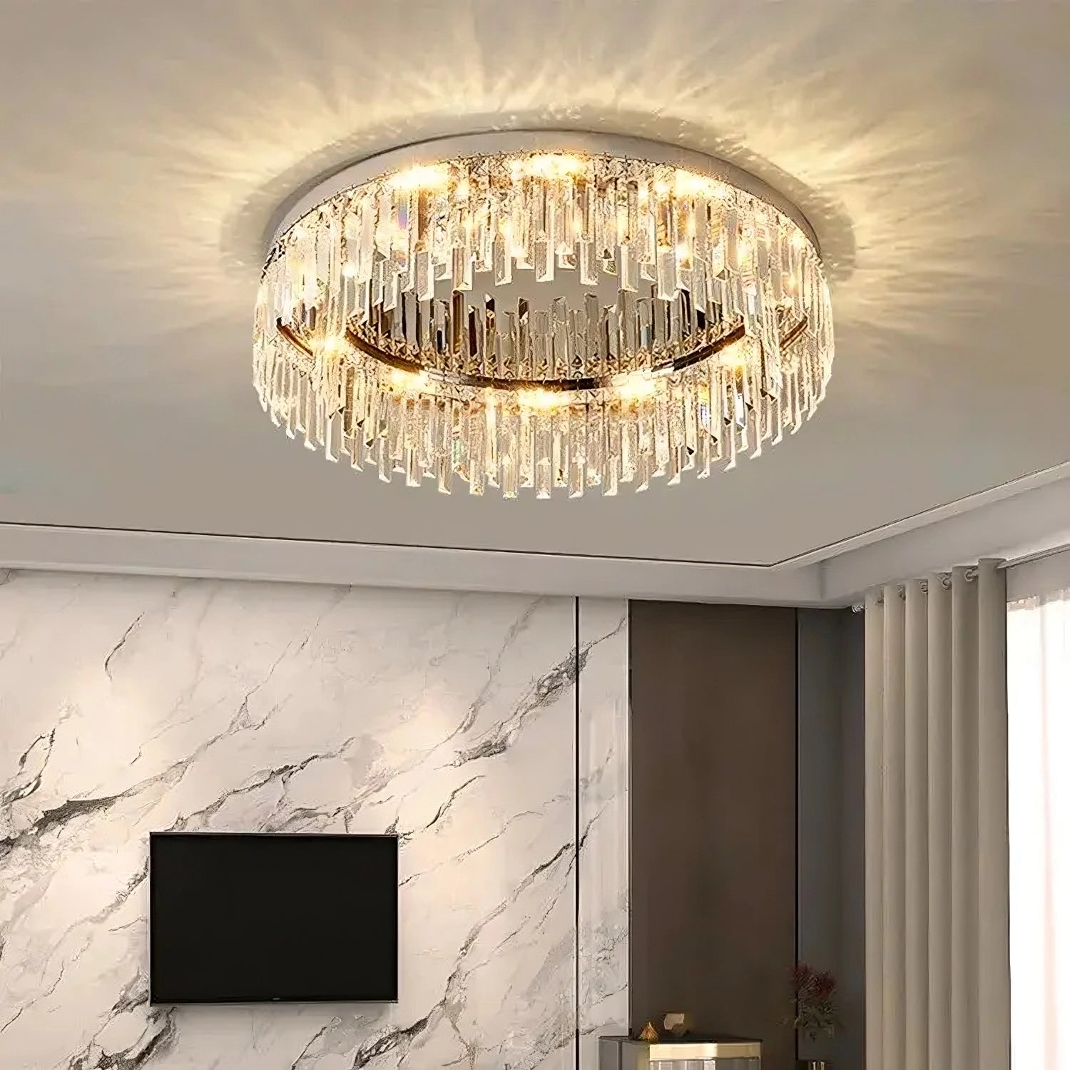 A modern living room with a Morsale.com Gio Flush Mount Crystal Ceiling Light featuring handmade clear crystal, casting intricate light patterns on the ceiling. The room has a minimalist design with a black TV mounted on a marbled wall and curtains partially opened, letting in natural light.