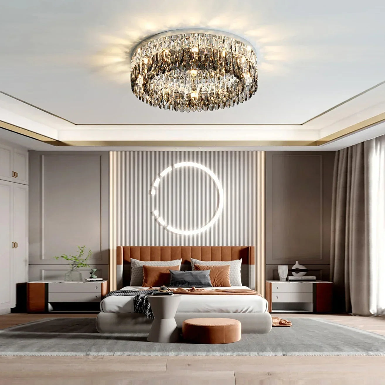 A modern bedroom featuring a large Giano Crystal Ceiling Light from Morsale.com on the ceiling. There is a bed with an upholstered headboard adorned with pillows and a throw blanket. A round illuminated wall decor hangs above the bed. Two nightstands flank the bed, and a large window lets in natural light.
