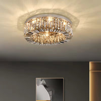 The Speccio Crystal Flush Mount by Morsale.com, a round modern smoke grey ceiling light with warm illumination, casts decorative shadows above a gray wall accented by abstract art and a gold-toned cabinet.