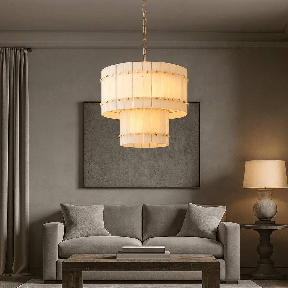 
                  
                    A modern living room with a beige sofa, wooden coffee table, table lamp, and the Morsale Valmont 2-Tier Marble Chandelier 23", casting a sculptural warm glow against neutral walls and curtains.
                  
                