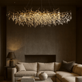 A modern living room with a beige sectional sofa, neutral decor, a ceramic vase on the coffee table, and a striking Albero Crystal Chandelier by Morsale.com hanging above. The space exudes warmth and elegant style.