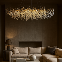 A modern living room with a beige sectional sofa, neutral decor, a ceramic vase on the coffee table, and a striking Albero Crystal Chandelier by Morsale.com hanging above. The space exudes warmth and elegant style.