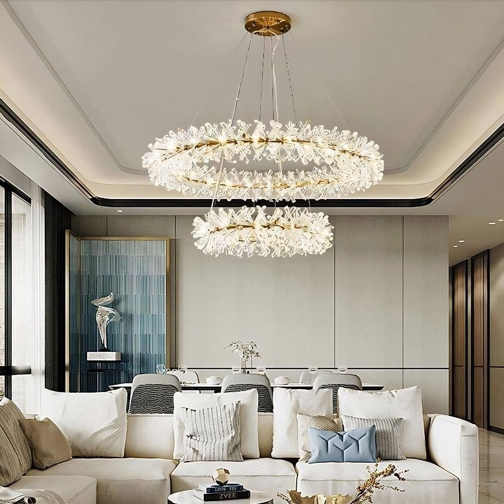 A luxurious modern living room with elegant white sofas, sleek decor, and the Mira Double Ring Crystal Chandelier from Morsale.com with flower-like elements, set against a backdrop of floor-to-ceiling windows and neutral tones.