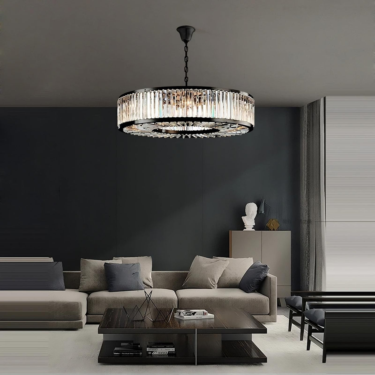 A modern living room with a beige sectional sofa, black and marble coffee table, and minimalist decor. A large Gio Crystal Modern Chandelier by Morsale.com hangs from the ceiling, casting soft, sophisticated lighting over the space. There's a sculpture on a cabinet in the background, enhancing the room's elegance.