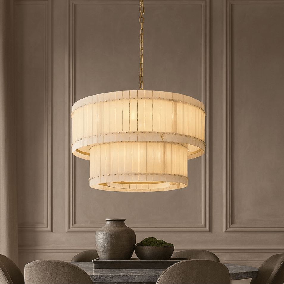 
                  
                    The Morsale Valmont 2-Tier Marble Chandelier 39" with cream panels hangs above a dark dining table set with a ceramic vase and green moss, set against a neutral paneled wall.
                  
                