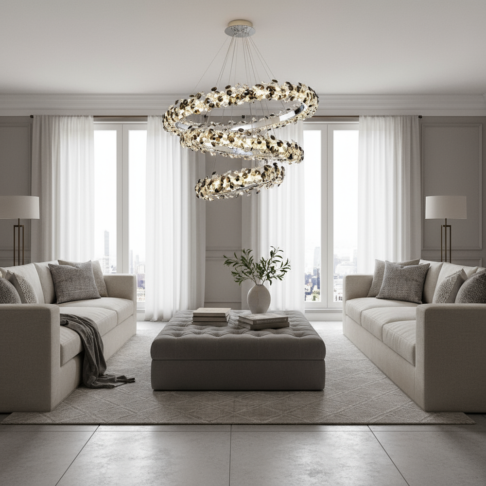 A modern living room with two beige sofas facing each other, a tufted ottoman in the center, a flower vase, floor lamps, large windows with sheer curtains, and the stunning Bigman Gardo Crystal Modern Chandelier overhead.