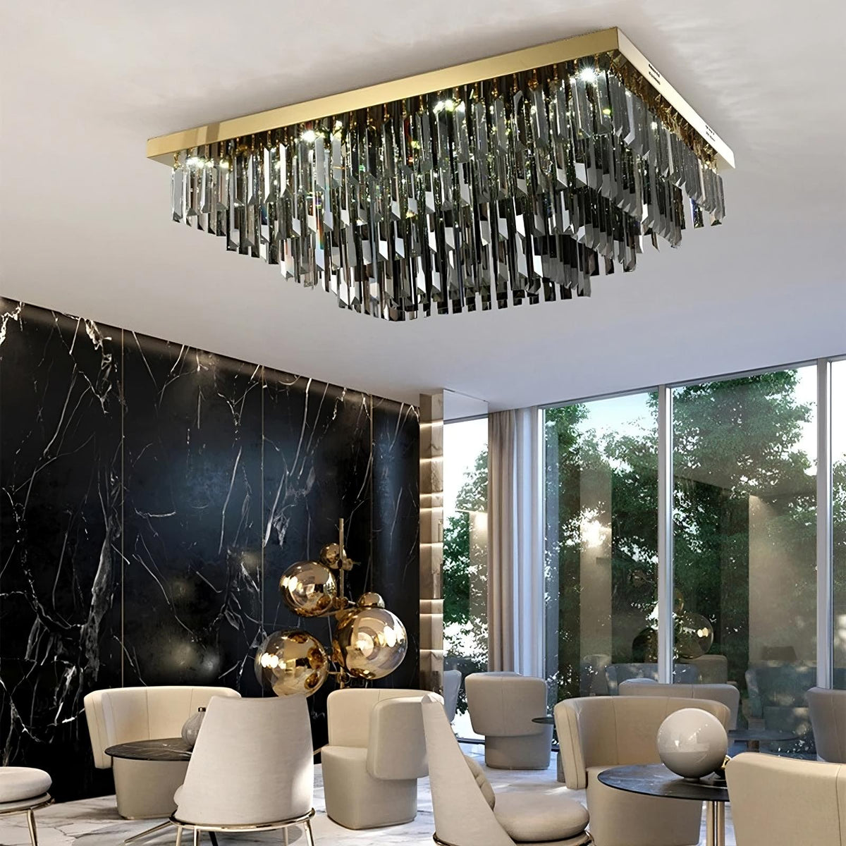 An elegant modern room with a large rectangular Gio Smoke Grey Crystal Ceiling Chandelier from Morsale.com hanging from the ceiling. The chandelier, made of multiple reflective metal strips, enhances the versatile lighting. The room features white chairs, a marble wall, and large windows with greenery visible outside.