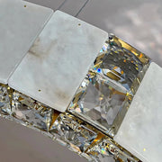 A close-up image shows a section of a luxurious Natural Marble & Crystal Modern Ceiling Light Fixture. The accessory from Morsale.com features large, square-cut, clear gemstones separated by rectangular, frosted metal or stone pieces with small holes. The design reflects light beautifully, reminiscent of a modern ceiling chandelier's sparkling effect.