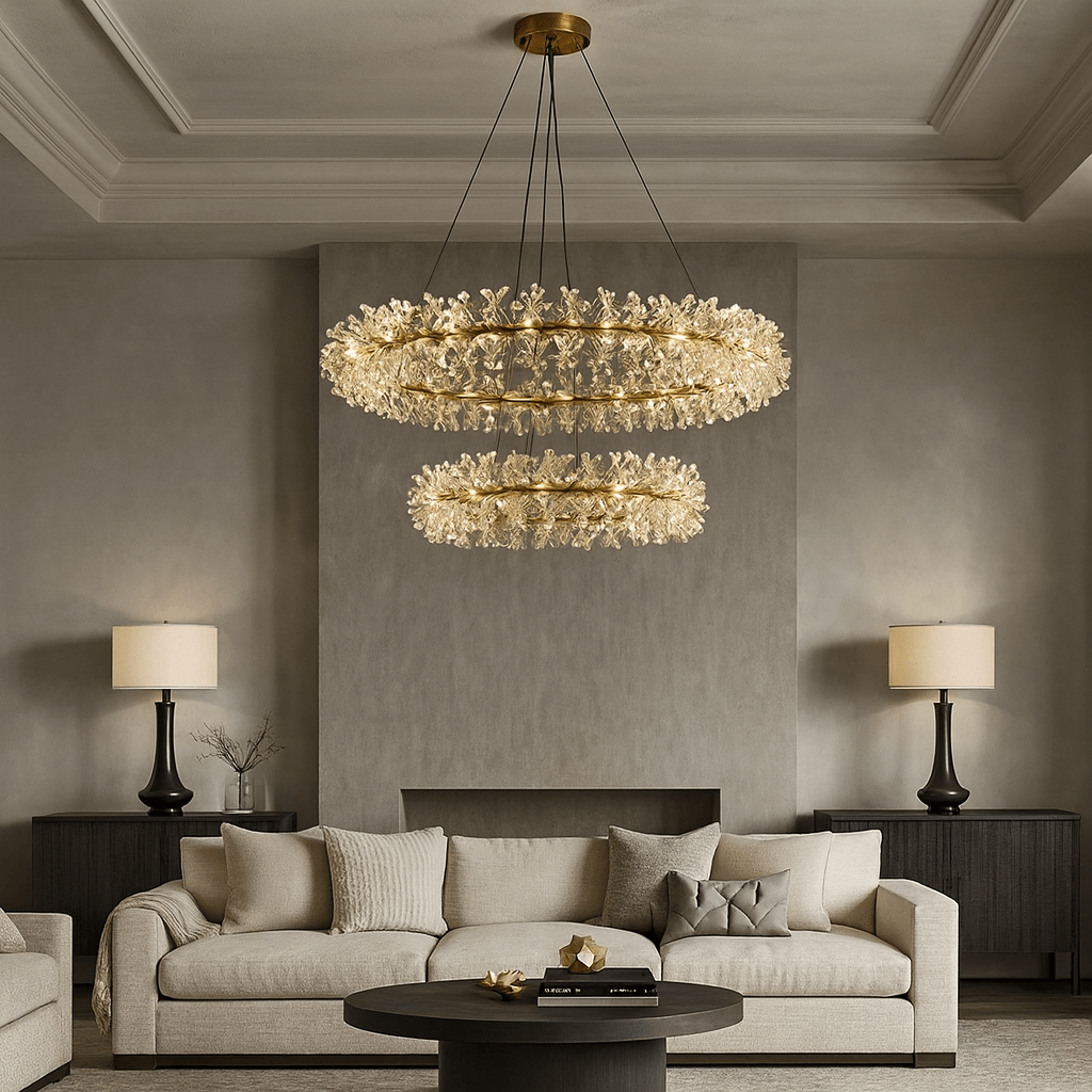 A modern living room with a beige sofa, dark wood side tables, matching table lamps, and a round black coffee table. Two Exton Crystal Chandeliers by Morsale.com hang from the ceiling, adding elegant lighting to the neutral space.
