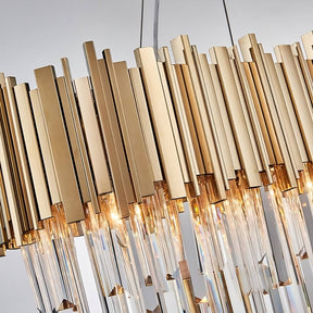 Elegant Gio Crystal Dining Room Chandelier from Morsale.com consisting of numerous vertical gold metal rods and hanging crystal prisms, illuminated with warm LED bulbs, suspended against a soft-focus background.