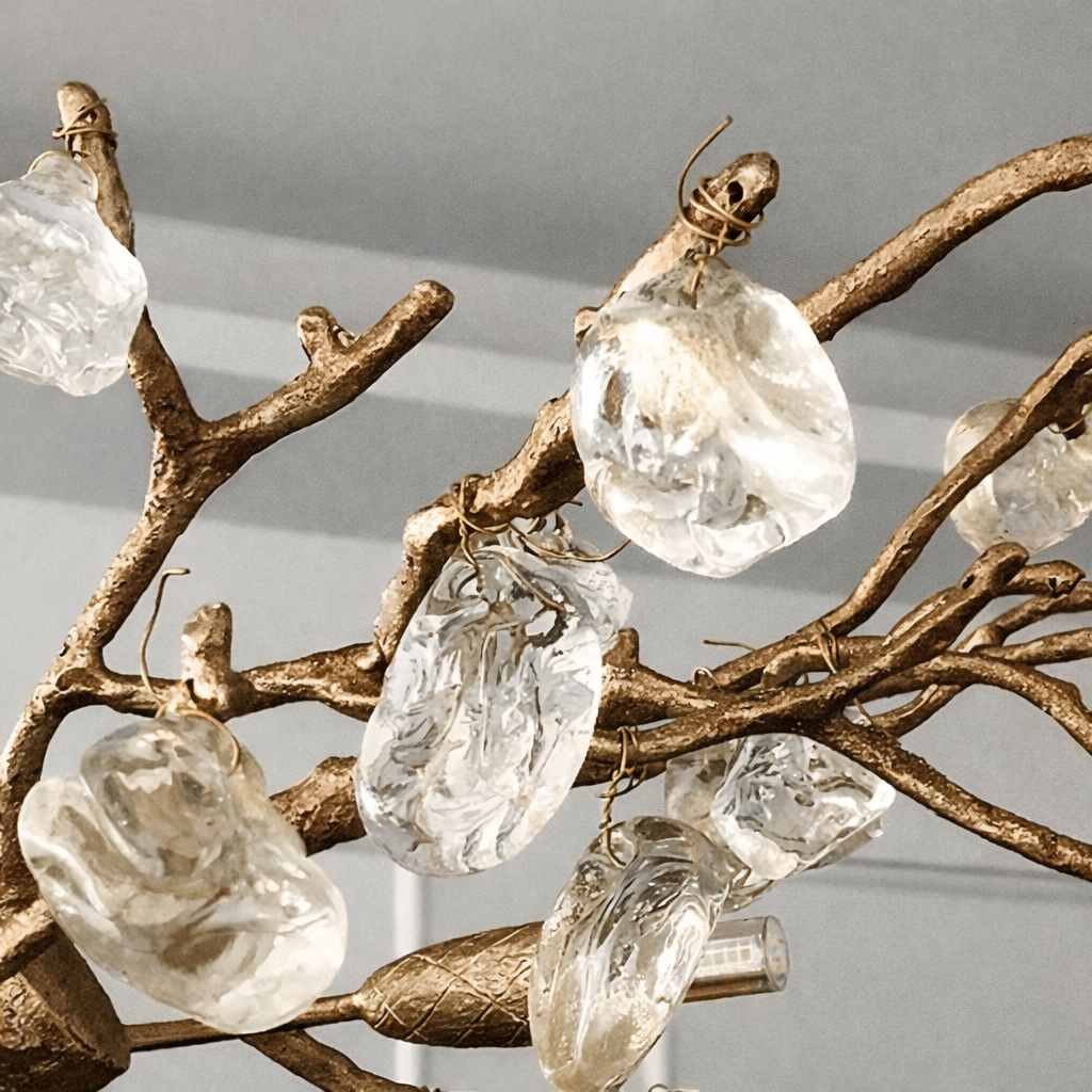 A close-up of the Bigman Albero Copper & Crystal Chandelier showcases its decorative copper branches and large crystal ornaments, reminiscent of modern lighting, set against a soft gray background.