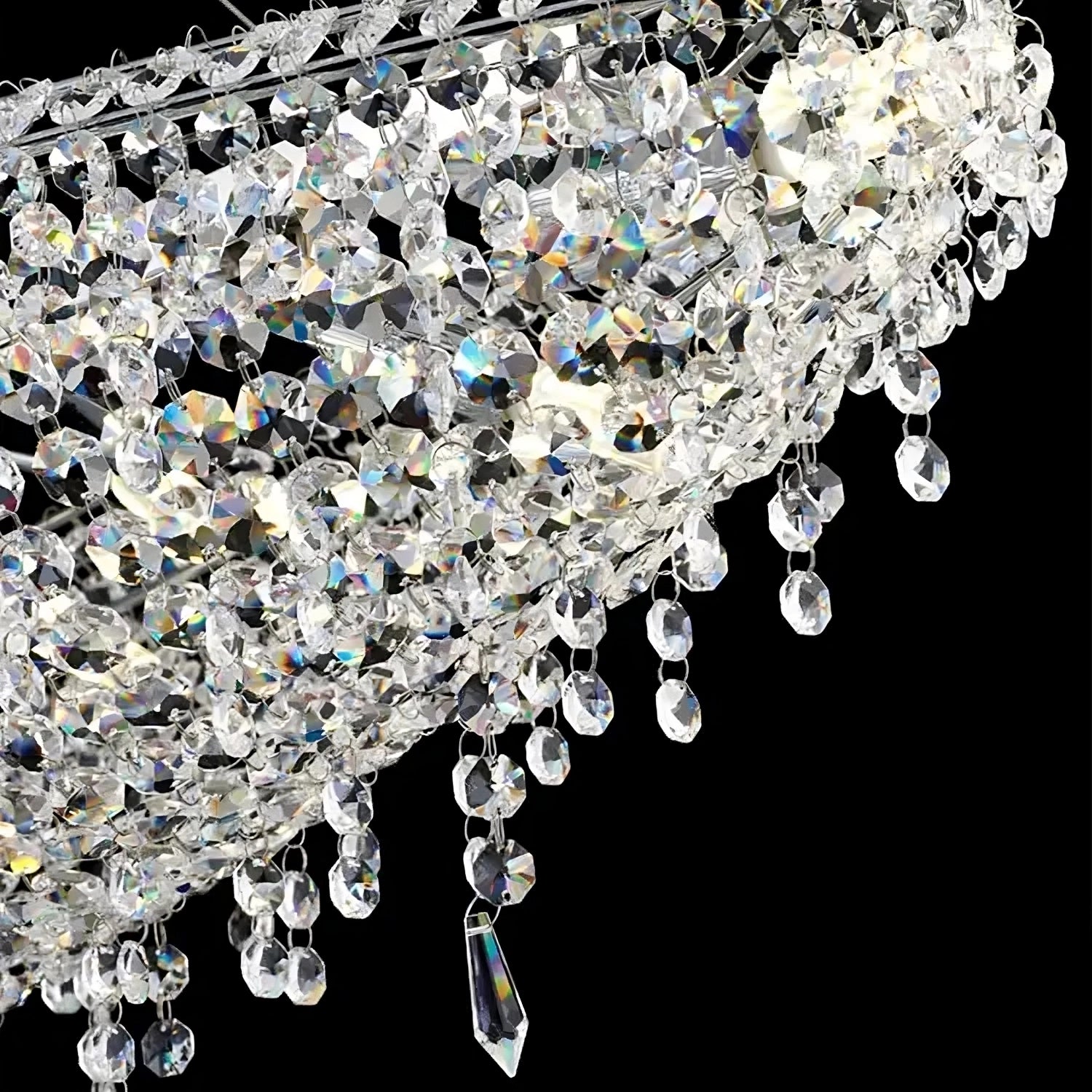 A close-up shot of the Alleri Crystal Chandelier For Dining Room by Morsale.com against a black background. This dining room chandelier showcases numerous clear, faceted premium crystals and pendants, creating a luxurious, sparkling effect. The crystals reflect light from E14 LED bulbs, producing a stunning spectrum of colors.