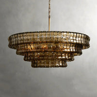 The Riviera Modern Chandelier by Morsale hangs against a neutral grey background, featuring amber-tinted French glass segments and a brass chain. Its modern lighting highlights the concentric, cascading tiers for an elegant, vintage-inspired style.