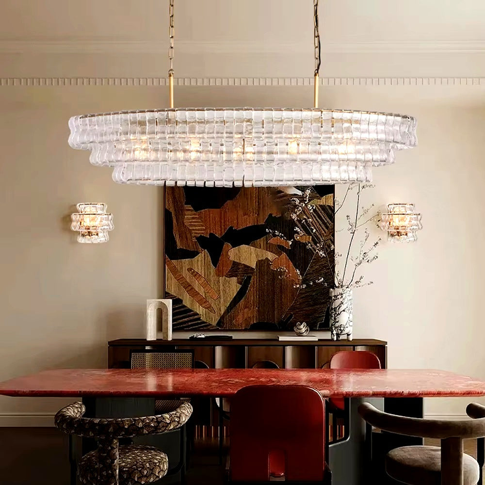 
                  
                    Dining room with a large crystal chandelier, red table, and abstract painting on the wall.
                  
                