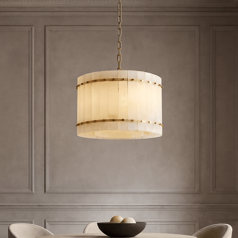 The Morsale Valmont Marble Round Chandelier 16" with a gold chain hangs above a round table holding three apples, set against neutral walls adorned with elegant classic molding.