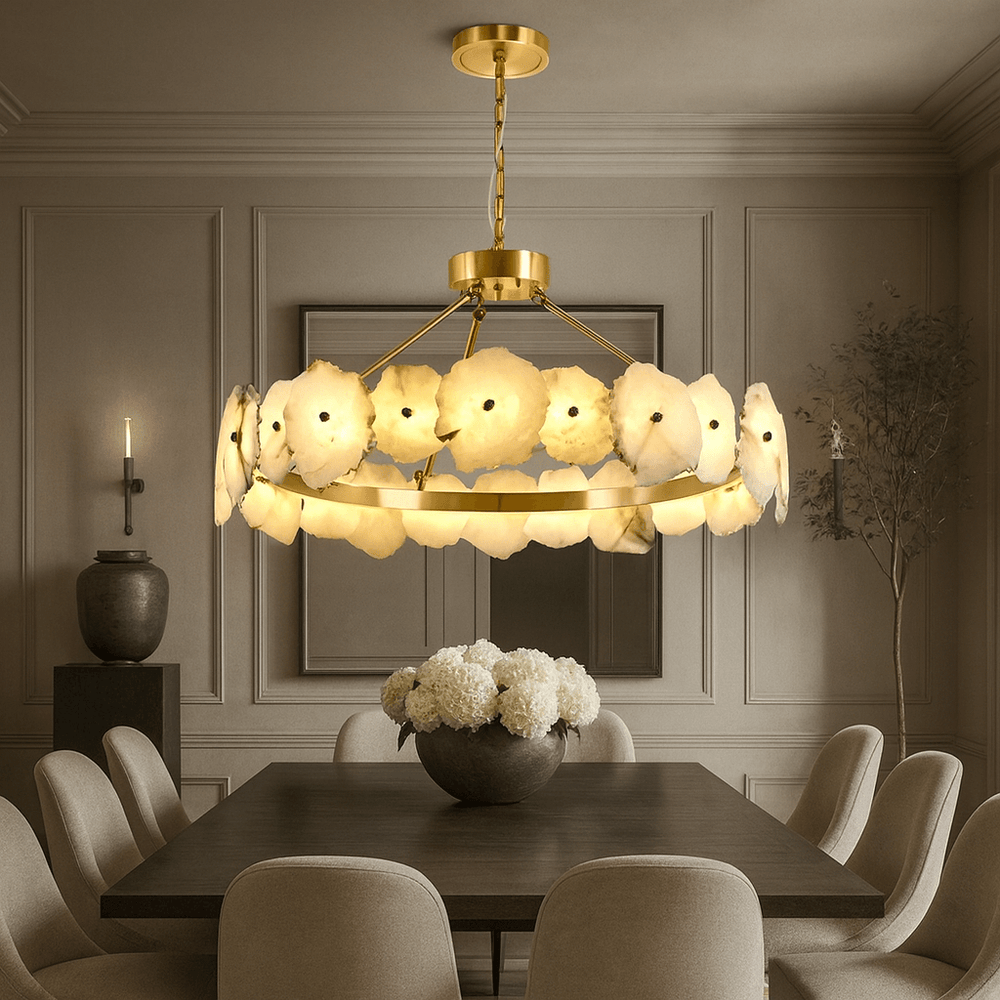 
                  
                    A modern dining room showcases the Bigman Corton Marble & Brass Chandelier, a dark wooden table with six light upholstered chairs, a vase of white flowers, and neutral-toned paneled walls.
                  
                