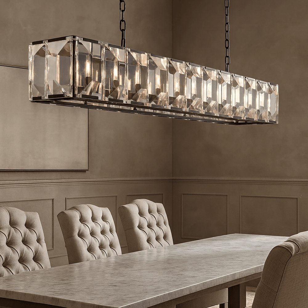 A modern dining room showcases the Brookhill Crystal Rectangular Chandelier by Morsale.com above a long marble table, framed by tufted beige chairs and taupe paneled walls.